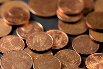 Different amounts of scattered European coins on a black background.