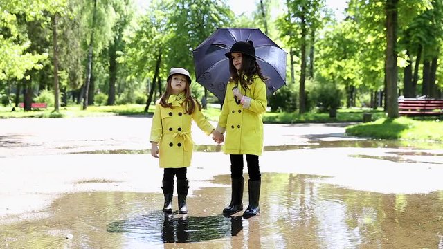 young girls running throught the puddles in the park after the rain