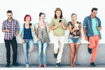 Group of friends watching on their smart mobile phones outdoor - Young generation having fun with...