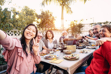 Happy family cheering and toasting with red wine glasses at dinner outdoor - People with different...