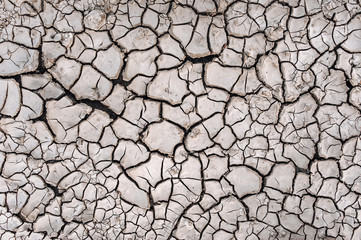 Dry cracked gray ground. Natural background. Chernozem and agriculture in the period of extreme drought. The texture of the desert close up.