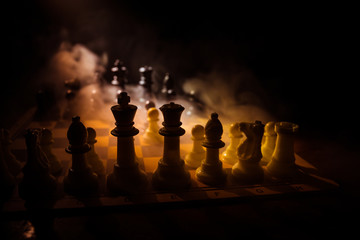 Chess board game concept of business ideas and competition. Chess figures on a dark background with smoke and fog.