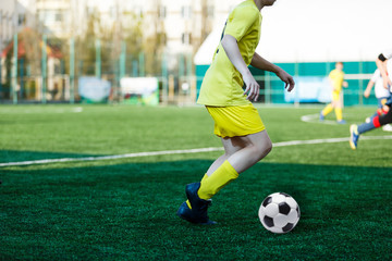 Football teams boys in yellow white sportswear play soccer on the green field. Dribbling skills. Team game, Training, active lifestyle, hobby, sport for kids concept