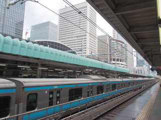 View from the railway platform of Tokyo Train Station with modern office towers under blue sky