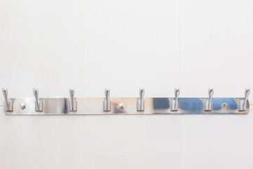 Bathroom hook mounted at the wall in the bathroom. Hooks for clothes and towels in the bath. Metal hooks for towels.