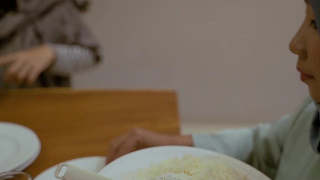 asian muslim woman with rice eating in dining room