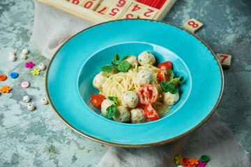 Children's pasta with meatballs and basil among children's toys 