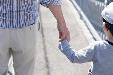 Child and senior man holding hands