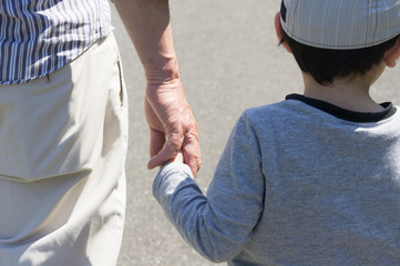Child and senior man holding hands