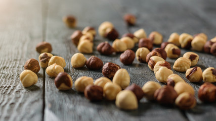 A lot of roasted hazelnuts scattered on a wooden table.