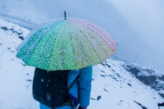 White landscape and thick snow in winter looking frosty and cold,a person standing with colorful rainbow umbrella, snow falling, bad weather, background - image