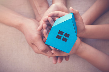 Adult and child hands holding white house, family home and homeless shelter, social distancing...