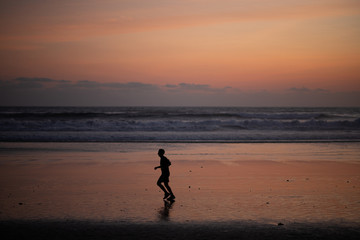 Fototapeta na wymiar Silouette of man jogging on beach at sunset