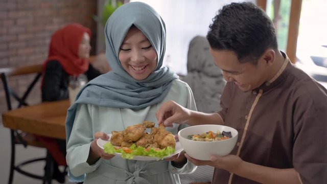portrait of husband and wife serving food for friend and family for break fasting together during ramadan