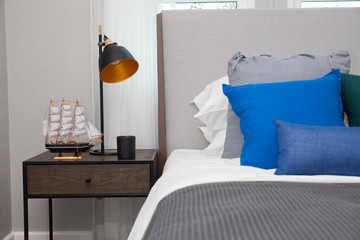 Modern bedroom with blue pillows and black lamp on table