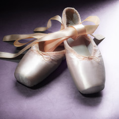 Pointe shoes ballet dance shoes with a bow of ribbons beautifully folded on a dark background.
