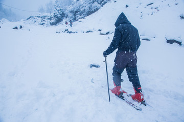 Man learning skiing with the help of trainer on a snowy day, adventurous sports activity, solo...