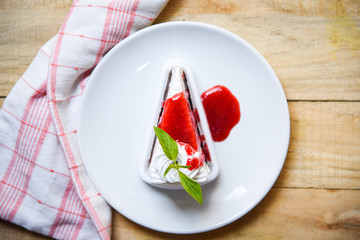 Crape cake slice with strawberry sauce on white plate on table wood