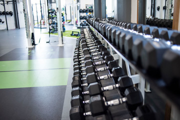 Closeup view of a rack of black dumbbells in a gym
