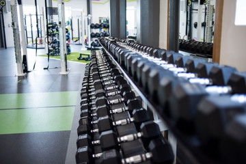 Closeup view of a rack of black dumbbells in a gym