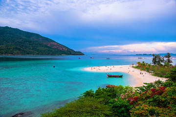 Beach that extends into the sea Looking out to see the island And blue sky There are many boats floating in the emerald green sea of the Andaman Sea. At Sunrise Beach, Koh Lipe, Satun, Thailand
