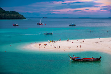 Beach that extends into the sea Looking out to see the island And blue sky There are many boats floating in the emerald green sea of the Andaman Sea. At Sunrise Beach, Koh Lipe, Satun, Thailand