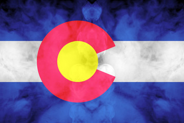 The national flag of the US state Colorado in against a gray smoke on the day of independence in...