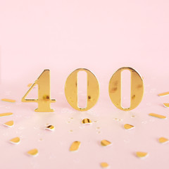 The number 400 is gold numbers on a pink background and golden confetti. Space for text...