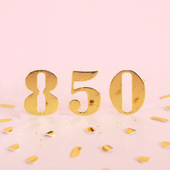 The number 850 in golden numbers on a pink background and golden confetti. Space for text...