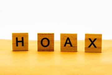 HOAX word written in wooden blocks on brown paper.