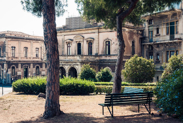 Sicily, beautiful cityscape of Italy, historical street of Catania, facade of old buildings with wooden bench.