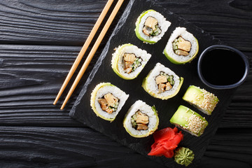 Japanese rolls wrapped in avocado with omelet, sesame and cucumber closeup on a plate. horizontal top view