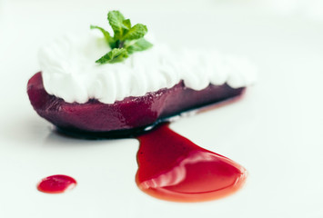 Traditional greek dessert, pear in syrup, with mint and with whipped cream, fork and white plate.
