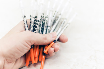 Pile of medical syringes for insulin for diabetes in woman hand
