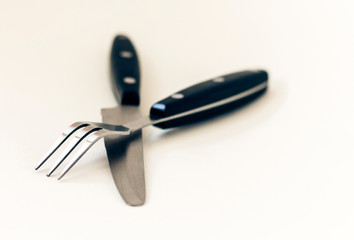 Close up knife and fork crossed, isolated on white background.