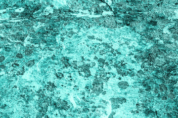 Fototapeta na wymiar Vintage azure background. Rough painted wall of turquoise color. Imperfect plane of cyan colored. Uneven old decorative toned backdrop of aqzure tint. Texture of teal hue. Ornamental stony surface.