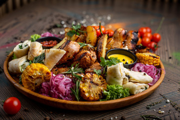 Tasty dish with meat and vegetables, baked pork, cowboy grill, grilled potatoes with sauce. Assorted tasty grilled meat with vegetables and herbs