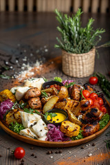 Fototapeta na wymiar Tasty dish with meat and vegetables, baked pork, cowboy grill, grilled potatoes with sauce. Assorted tasty grilled meat with vegetables and herbs