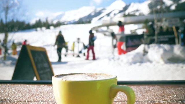 A hot cappucino steams at the base of a ski resort.