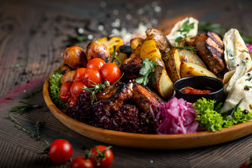Tasty dish with meat and vegetables, baked pork, cowboy grill, grilled potatoes with sauce. Assorted tasty grilled meat with vegetables and herbs