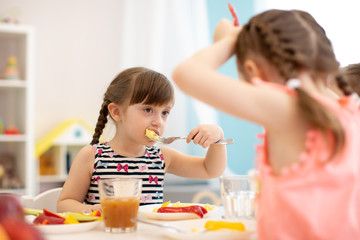 Kids have lunch in daycare, kindergarten or home. Child girl eating healthy food