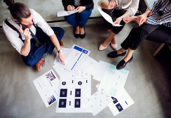 A midsection of business people sitting on the floor in an office. Top view.