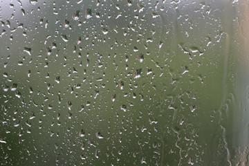 Raindrops on window glass during the rain close up. Natural background