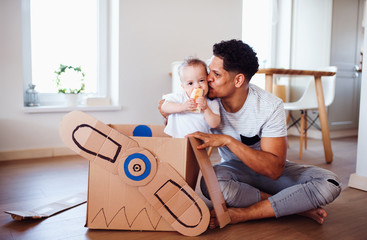 Father and small toddler son indoors at home, playing.