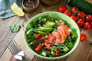 Diet menu, Vegan food. Healthy salad with quinoa, arugula, Tomatoes, Salmon and Avocado on rustic table.