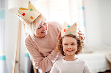 A portrait of small girl with grandmother at home, having fun.
