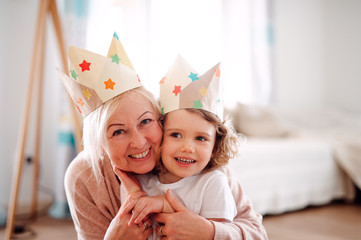 A portrait of small girl with grandmother hugging at home.