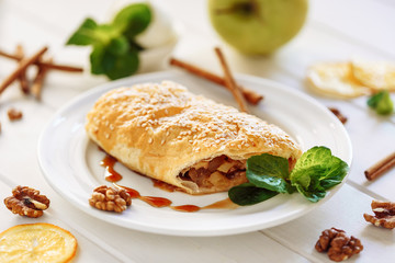 Apple Pastry Strudel Cake Dessert Pie Closeup. Austrian Puff Piece with Cinnamon and Sesame, Mint Leaf on White Plate. Bakery Cutted for Birthday Breakfast. Homemade Apfelstrudel Gourmet Crust