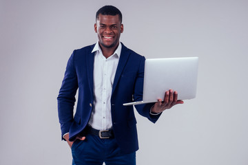 Happy successful young african american businessman portrait wearing a crown holding a laptop...