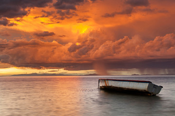Fischerboot auf dem Hintergrund eines dramatischen Sonnenuntergangs. Mauritius.